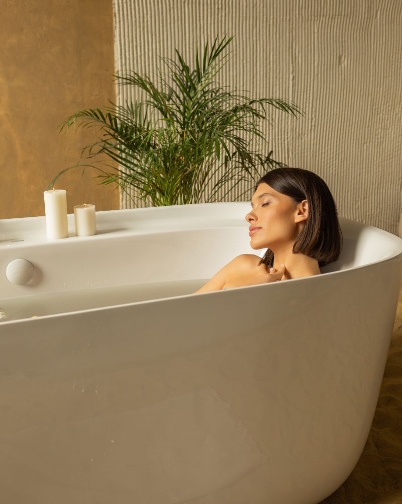  A beautiful woman relaxes in a flower-filled bathtub, indulging in a calming bath tea blend of plants and essential oils.